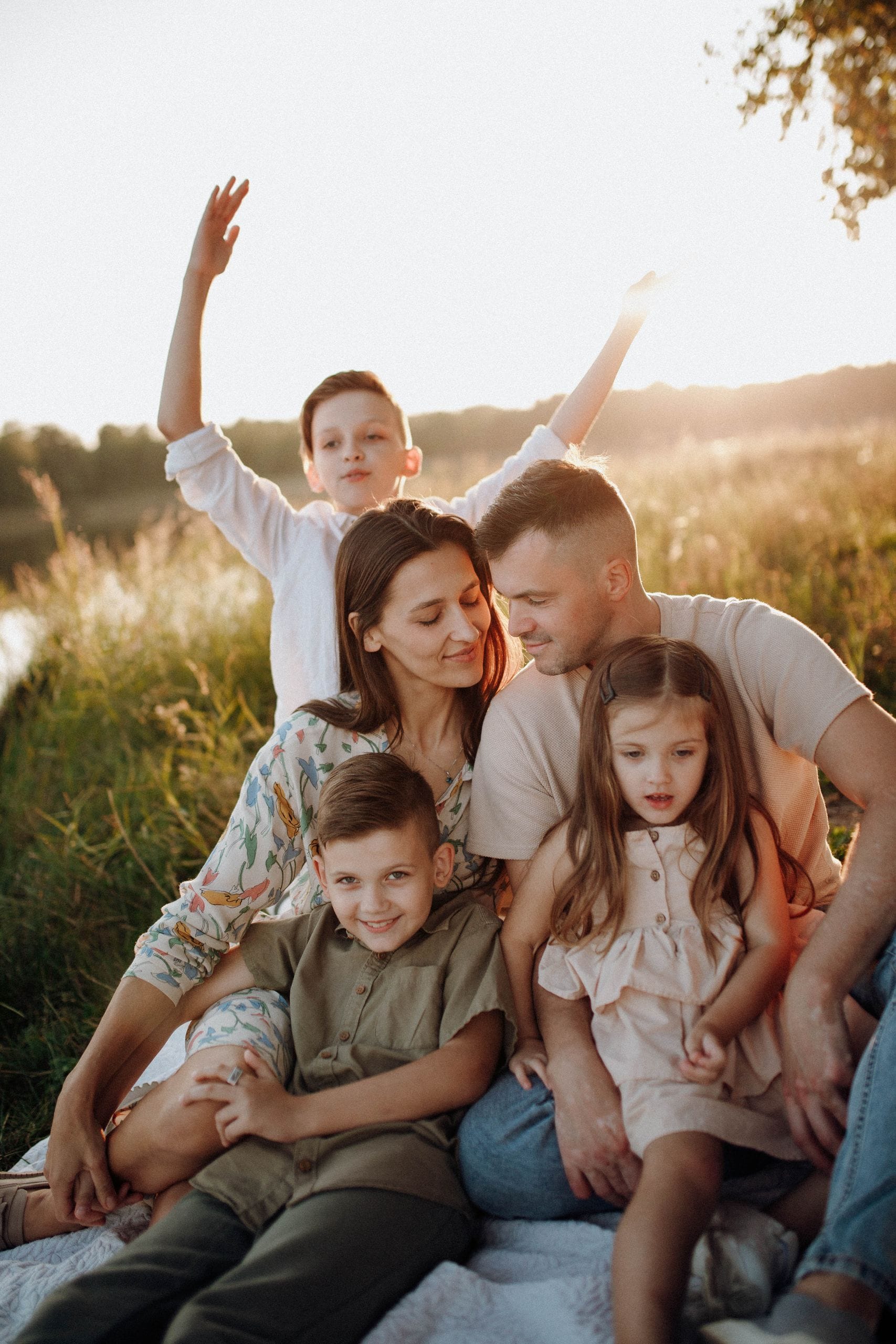 A family enjoying a sunny outdoor picnic together in a field.